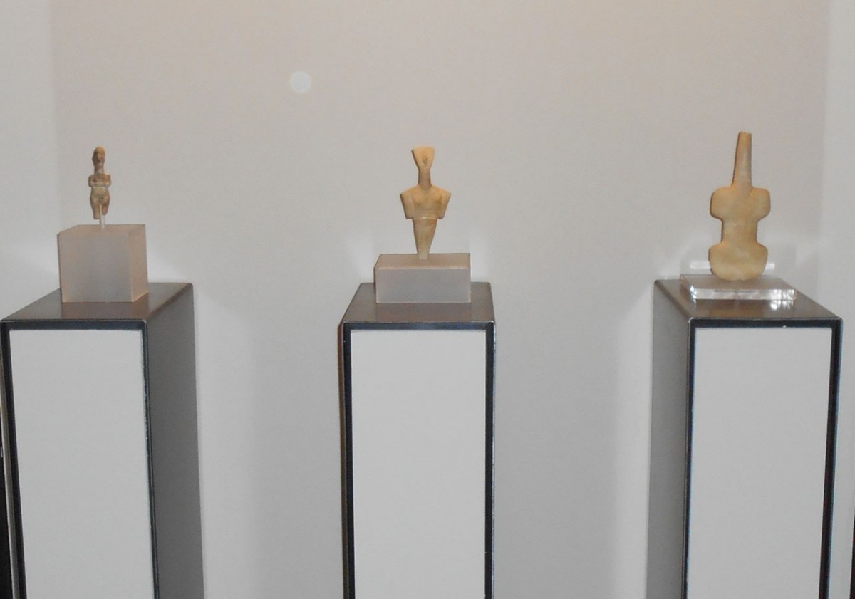 Τα τρία από τα τέσσερα ειδώλια του Μουσείου Κυκλαδικής Τέχνης όπως παρουσιάζονται στις προθήκες της έκθεσης.