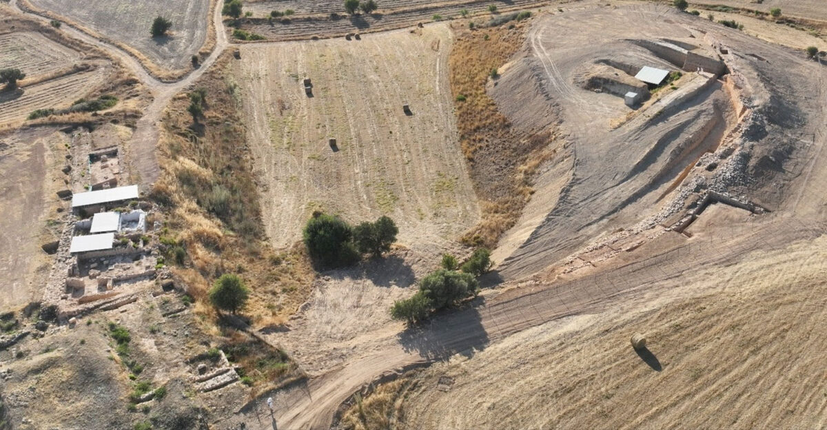 Εικ. 12. Λαόνα: διακρίνεται το τείχος (δεξιά/βόρεια). Χατζηαπτουλλάς (αριστερά/νότια): διακρίνεται το ανάκτορο και το εργαστηριακό σύμπλεγμα με προσωρινές οροφές προστασίας. Φωτογραφία από UAV (drone) από ανατολικά προς δυτικά. Πηγή εικόνας: Τμήμα Αρχαιοτήτων Κύπρου.